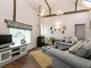 ein Wohnzimmer mit einem Sofa und einem TV in der Unterkunft Heron Barn in Little Hautbois