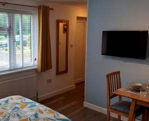 a room with a table and a television on a wall at The Studio in Felpham