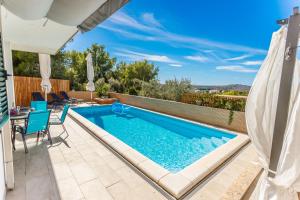 a swimming pool in a backyard with a table and chairs at Villa NONO Jure - Private Pool & Jacuzzi, Milna Brač in Milna