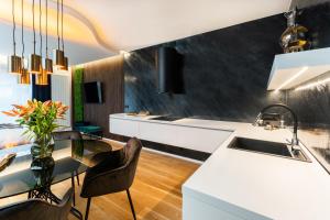 uma cozinha com balcões brancos e uma mesa de vidro em MOLI Apartmán s privátní saunou - MOLO Lipno Resort em Lipno nad Vltavou