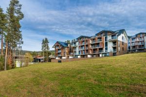 a large building on top of a grassy hill at MOLI Apartmán s privátní saunou - MOLO Lipno Resort in Lipno nad Vltavou