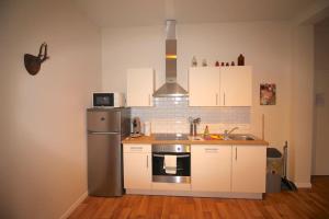 cocina con armarios blancos y nevera de acero inoxidable en Appartement 3 chambres en plein centre ville, en Lieja