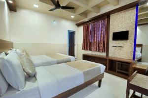 a bedroom with two beds and a flat screen tv at Mannars Deluxe Lodge in Mysore
