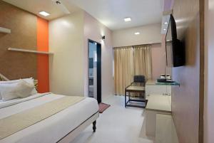 a bedroom with a bed and a desk and a television at Mannars Deluxe Lodge in Mysore