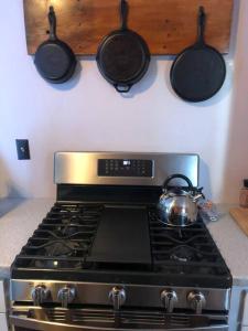a stove top with pots and pans hanging above it at APPLEJAX cabin steps from a u pick orchard in Sandisfield