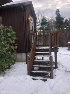 a cabin with a staircase in the snow at APPLEJAX cabin steps from a u pick orchard in Sandisfield