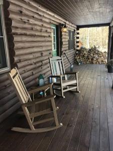 two rocking chairs on a porch of a log cabin at APPLEJAX cabin steps from a u pick orchard in Sandisfield