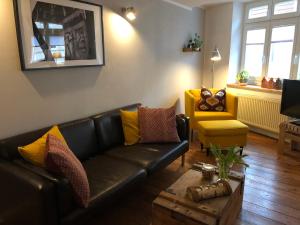 ein Wohnzimmer mit einem Ledersofa und einem gelben Stuhl in der Unterkunft Altstadthaus TimpeTe in Wismar