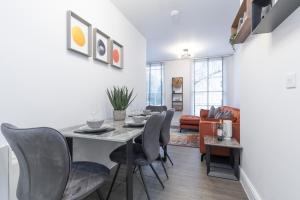a dining room and living room with a table and chairs at Elliot Oliver - Luxury 2 Bedroom Regency Apartment With Parking & EV Charger in Cheltenham