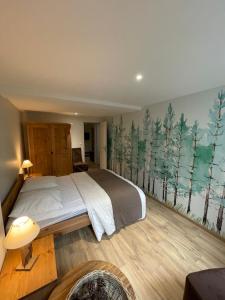 een slaapkamer met een bed met een muurschildering van bomen bij LE LOFT et le T2, Le Mont Dore, au pied de La Dordogne in Le Mont-Dore