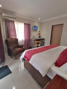 um quarto com uma cama, uma cadeira e uma secretária em Rondy Bosch Lodge em Louis Trichardt