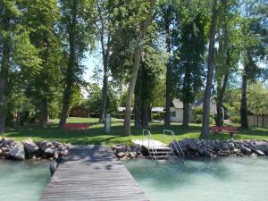 un puente de madera sobre un río con dos sillas. en Fonyód Camping & Apartman en Fonyód