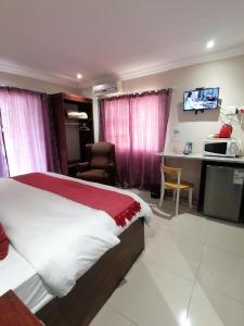 a bedroom with a bed and a desk with a microwave at Rondy Bosch Lodge in Louis Trichardt