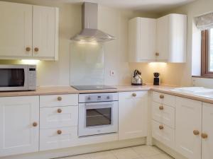 een keuken met witte kasten en een fornuis met oven bij Woodpecker Cottage - Ukc3412 in Bolton by Bowland