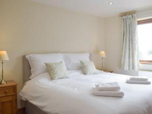 een wit bed met twee handdoeken erop bij Woodpecker Cottage - Ukc3412 in Bolton by Bowland