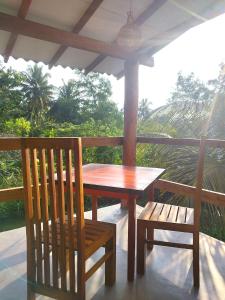 a wooden table and two chairs on a porch at EKUKU lake houses in Kumbalgama