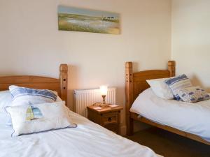 a bedroom with two beds and a lamp on a table at Bryn Golau in Llanfaethlu