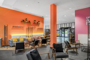 a lobby with chairs and tables and orange walls at Neuchâtel City Hôtel in Neuchâtel