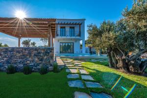 a house with a stone wall and a yard at Stargaze Villas in Panormos Skopelos