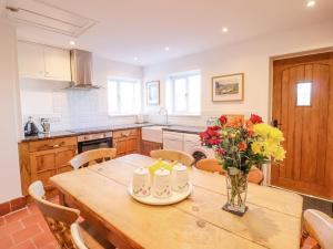 a kitchen with a wooden table with flowers in a vase at Alwyn Cottage in Llangollen