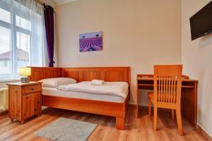 a bedroom with a bed and a desk and a chair at Penzion pod Radyni in Starý Plzenec