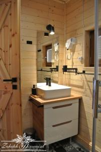 La salle de bains est pourvue d'un lavabo blanc et d'un mur en bois. dans l'établissement Zakątek DZIEWIĘĆSIŁ, à Przyborów