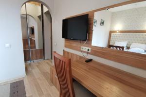 Zimmer mit einem Schreibtisch, einem TV und einem Bett in der Unterkunft Вілла Калина in Truskawez