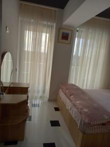 a bedroom with a bed and a desk and windows at Apartament 2 dormitoare și living bloc nou in Năvodari