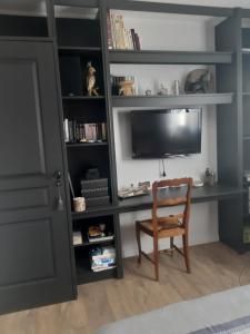 a room with a desk with a chair and a tv at L'Olivier in Beuzeville