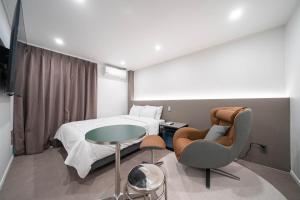 a hotel room with a bed and a chair and a table at Jawoori Hotel Incheon Songdo in Incheon