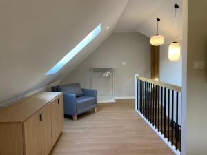 a living room with a blue chair and a staircase at Apartamenty Paproć i Malina - 300 metrów do centrum in Karpacz