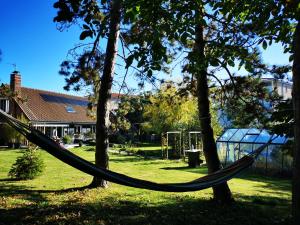 a hammock hanging between two trees in a yard at La Maison des Oiseaux. Roulotte in Achicourt