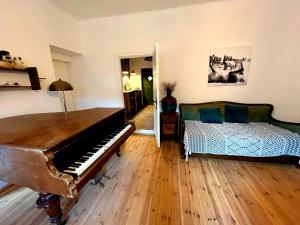 a living room with a piano and a bed at Dömörkapu Rengeteg Vendégház in Szentendre