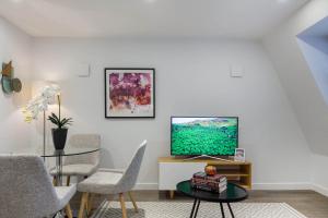 ein Wohnzimmer mit einem TV und einem Tisch in der Unterkunft Urban Chic - Rathbone in London