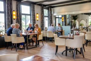 een groep mensen die aan tafel zitten in een restaurant bij Hotel Restaurant Eeserhof in Ees