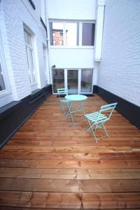 um pátio com 2 cadeiras e uma mesa num piso de madeira em Charmant appart 2 ch avec terrasse en centre ville em Liège