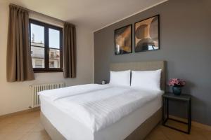 une chambre avec un grand lit blanc et deux fenêtres dans l'établissement Bohemian Dreams Apartments and Suites by Dwellfort, à Prague