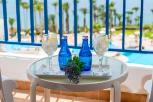a table with three blue bottles and glasses on it at Ascos Coral Beach Hotel in Coral Bay