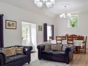 a living room with two leather couches and a dining room at Tyn Y Coed in Bettws-Evan