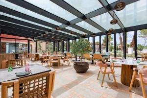 a restaurant with tables and chairs and windows at Kimpton Aysla Mallorca by IHG in Santa Ponsa