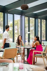 a group of people sitting at a table in a restaurant at Kimpton Aysla Mallorca by IHG in Santa Ponsa