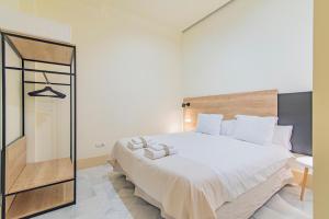 a bedroom with a large white bed and a mirror at Mosaiko Homes Catedral Granada in Granada