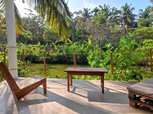 a porch with a wooden table and a chair at EKUKU lake houses in Kumbalgama