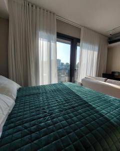 1 dormitorio con 1 cama verde grande y ventana en MyHome - Studio de Luxo próximo ao Shopping Iguatemi, en Porto Alegre