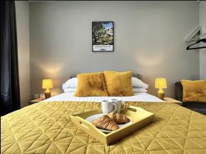 Luxury Harrogate Flat with Free Parking في هاروغايت: غرفة في الفندق مع سرير مع صينية من الكرواسون
