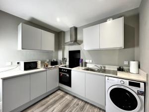 a kitchen with white cabinets and a washer and dryer at Luxury Harrogate Flat with Free Parking in Harrogate