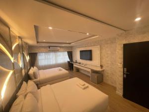 a small room with two beds and a television at Masa Hotel فندق الماسة شارع العرب in Bangkok