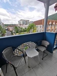 two chairs and a table on a balcony with a view at Sea Boss Homestay in Kata Beach