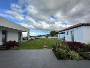 un patio trasero de una casa con un patio verde en Serenity Azores - Casa da Aldeia en Nordestinho