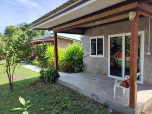 a porch of a house with a white chair on it at Our Village Bungalows in Koh Mook